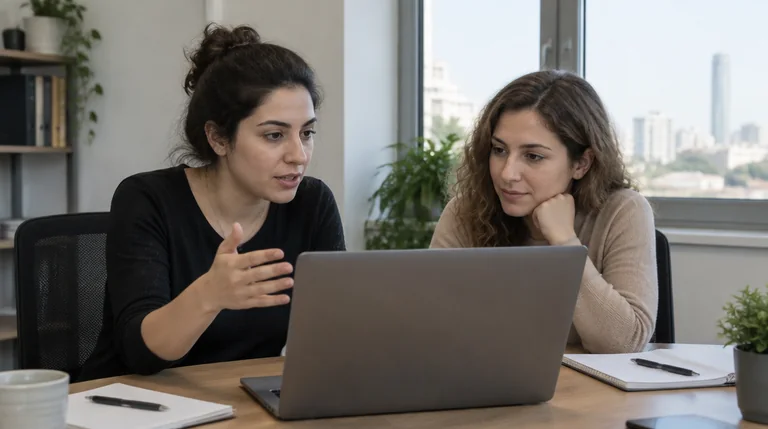 שני עובדים יושבים ליד מחשב נייד במשרד ומתייעצים